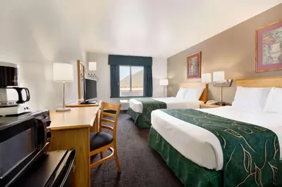 a hotel room with two beds and a flat screen tv at Travelodge by Wyndham Yermo in Yermo