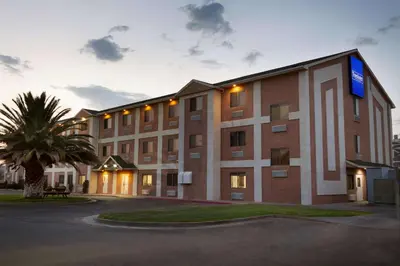 a large building with a palm tree in front of it at Travelodge by Wyndham Yermo in Yermo