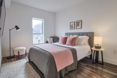 a white bedroom with a large bed with pink pillows at Modern 2BD - 5 min to Santa Monica Pier! in Los Angeles