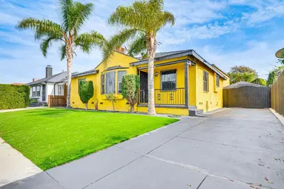 a yellow house with palm trees in a yard at 8 Mi to Dtwn LA Apt with Shared Patio! in Los Angeles