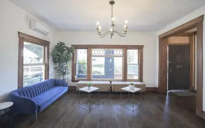 a living room with a blue couch and some windows at Burlington Hostel in Los Angeles