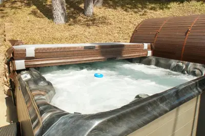 a hot tub in a backyard with a wooden deck at Bear Creek Haven -Nestled between the Village & Lake! in Big Bear Lake