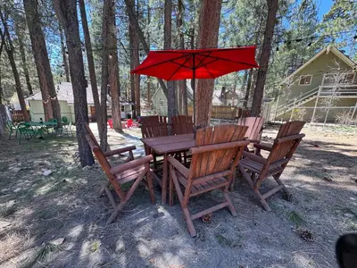 a wooden table and chairs with a red umbrella at Mountain Xscape - Hot Tub, Fireplace, Deck, Barbeque in Big Bear Lake