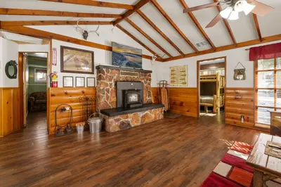 a living room with a stone fireplace and wooden floors at Mountain Xscape - Hot Tub, Fireplace, Deck, Barbeque in Big Bear Lake