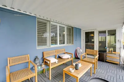 a porch with chairs and tables and a blue wall at 10 Mi to Redondo Beach Carson Home with Pool Table! in Carson