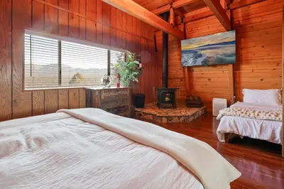 a bedroom with two beds in a room with wooden walls at The Cedar Bear Lodge, Jacuzzi with an Outdoor Patio & BBQ in Big Bear City Airport