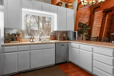 a kitchen with white cabinets and a sink and a window at The Cedar Bear Lodge, Jacuzzi with an Outdoor Patio & BBQ in Big Bear City Airport