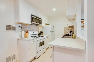 a kitchen with white cabinets and a stove top oven at 1 Mi to Dtwn Melrose Cozy Condo with Patio in Los Angeles