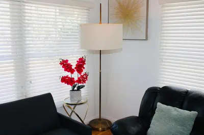 a living room with a black couch and a lamp with red flowers at Los Angeles Blue Nest in Monterey Park