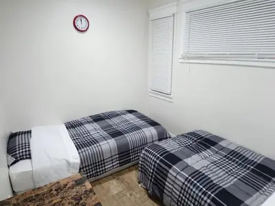 a bedroom with two beds and a clock on the wall at Vacation Unit is Available for Business and Family Trip in Long Beach