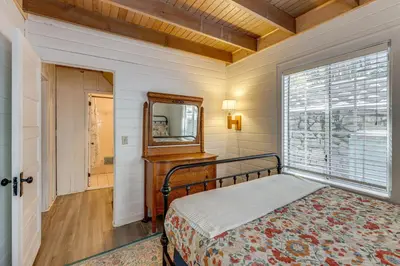 a bedroom with a bed and a mirror and a window at Walkable Green Gables Cottage in Lake Arrowhead in Lake Arrowhead