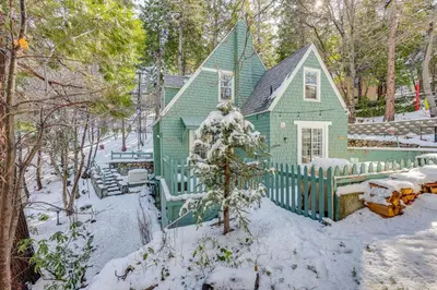 a green house with a fence in the snow at Walkable Green Gables Cottage in Lake Arrowhead in Lake Arrowhead