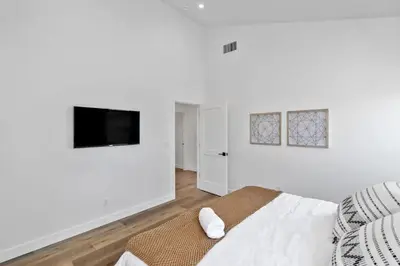 a white bedroom with a bed and a flat screen tv at Coastal Modern 3 Bed 2 Bath, Pet Friendly in Hawthorne