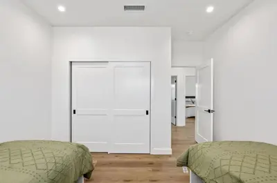 two beds in a bedroom with white walls and wood floors at Coastal Modern 3 Bed 2 Bath, Pet Friendly in Hawthorne