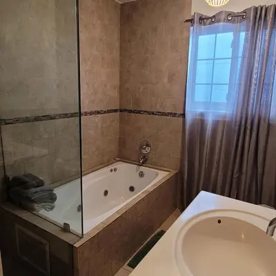 a bathroom with a tub and a shower and a toilet at 3 bedroom 2 bath home with Jacuzzi near Beverly Hills, wi-fi, Jacuzzi, Roku, BBQ, giant games family fun in Los Angeles