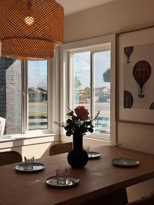 a dining room table with plates and a vase with flowers at Cozy Private Room A in S Central LA in Los Angeles