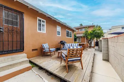 a wooden deck with chairs and a table and a building at Spacious Single Apt D In Santa Monica in Los Angeles
