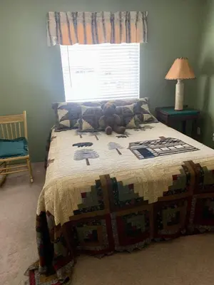 a bed with a quilt on it in a bedroom at Spacious cozy chalet huge deck over seasonal creek in Big Bear City Airport