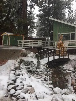 a snow covered yard with a house and a bridge at Spacious cozy chalet huge deck over seasonal creek in Big Bear City Airport