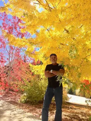 a man standing in front of a yellow tree at Spacious cozy chalet huge deck over seasonal creek in Big Bear City Airport