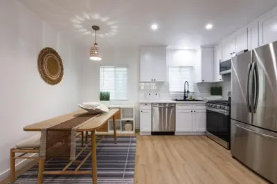 a kitchen with white cabinets and a wooden table at Stylish Long Beach Retreat Walk to Beach Bars in Long Beach