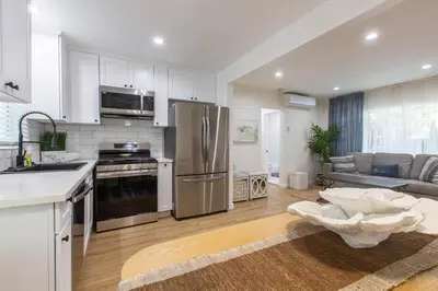 a kitchen with stainless steel appliances and a living room at Stylish Long Beach Retreat Walk to Beach Bars in Long Beach