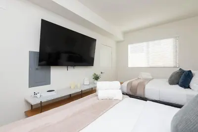 a white bedroom with two beds and a flat screen tv at Hollywood Apartment Near Walk of Fame in Los Angeles