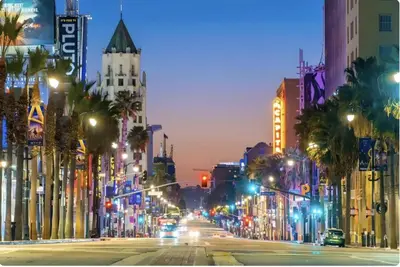 a city street at night with palm trees and buildings at Hollywood Apartment Near Walk of Fame in Los Angeles
