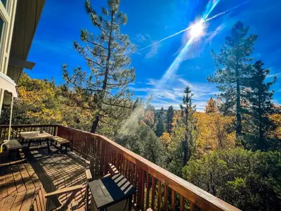 a deck with a table and benches on it at Stunning secluded Creekside A-Frame gameroom in Lake Arrowhead