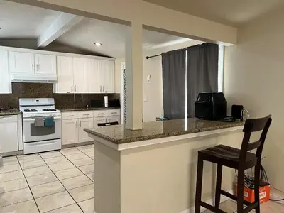 a kitchen with white cabinets and a bar with a chair at \u6b22\u8fce\u5165\u4f4fWest Covina\u7684\u56db\u5367\u4e8c\u536b\u7684\u72ec\u7acb\u623f\u5b50 in West Covina