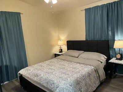 a bedroom with a large bed with blue curtains at \u6b22\u8fce\u5165\u4f4fWest Covina\u7684\u56db\u5367\u4e8c\u536b\u7684\u72ec\u7acb\u623f\u5b50 in West Covina