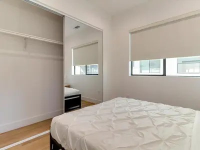 a white bedroom with a bed and two windows at Modern Luxe Retreat Two-Bedroom in Los Angeles