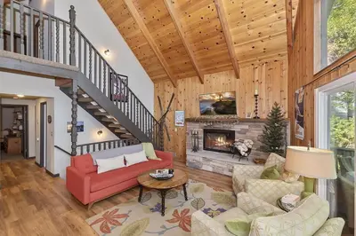 a living room with a red couch and a fireplace at Cozy Escape- Walking Distance to Village! in Lake Arrowhead