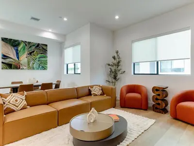 a living room with a brown couch and orange chairs at Modern Luxe Retreat Six-Bedroom in Los Angeles