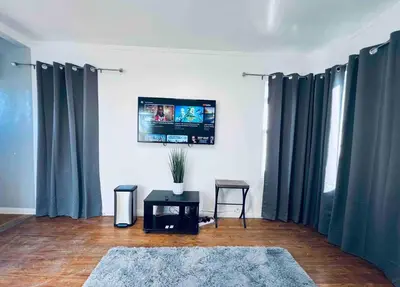 a living room with blue curtains and a tv at Beautiful private upstairs studio - USC, LAX, SOFI in Los Angeles