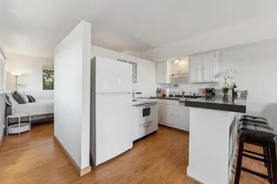 a kitchen with white cabinets and a white refrigerator at Whitney Oceanview Studio in Summerland