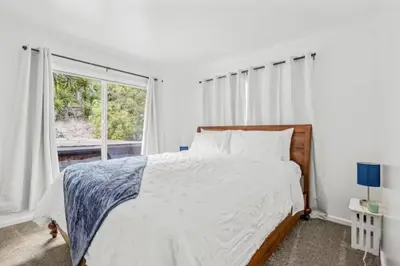 a white bedroom with a bed and a window at Summerland Beach Oasis- Pet Friendly in Summerland