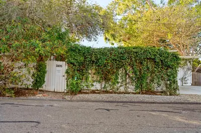 a ivy covered wall with a white gate and a building at Jennifers Room - Pet Friendly in Summerland