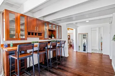 a kitchen with wooden cabinets and a bar with stools at The Grand Escape - Casita Sonrisa in Summerland