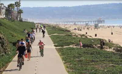 a group of people riding bikes on a sidewalk near the beach at 3BR Townhouse in Prime Manhattan Beach Location in Manhattan Beach