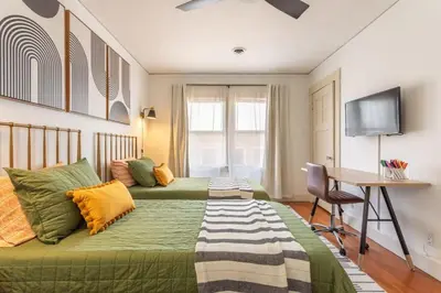 a bedroom with two beds and a desk and a television at Charming 1920s Hermosa Bungalow Steps from The Strand in Hermosa Beach