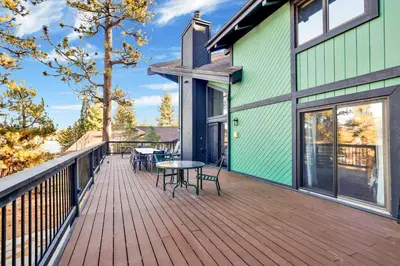 a wooden deck with tables and chairs on a house at The Birdhouse #2529 in Big Bear Lake