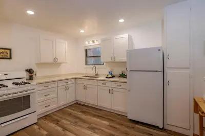 a white kitchen with white appliances and wooden floors at Kelley's Kabin #290 in Big Bear Lake