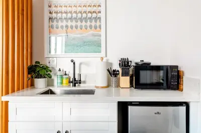 a kitchen counter with a microwave and a sink at Sleek Luxury Studio with Patio LAX & Beach Access in Los Angeles