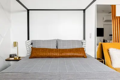 a bedroom with a large bed with an orange pillow at Sleek Luxury Studio with Patio LAX & Beach Access in Los Angeles