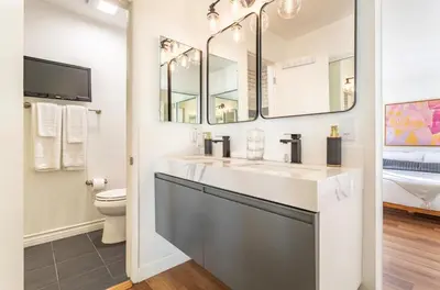 a bathroom with a sink and a toilet and mirrors at Exclusive Ocean & Pier View Family Escape in Manhattan Beach
