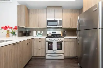 a kitchen with stainless steel appliances and wooden cabinets at Lovely 3BR Apt With Balcony And Rooftop Pool Plus Views in Los Angeles