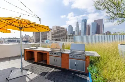 a patio with an outdoor kitchen with an umbrella at Lovely 3BR Apt With Balcony And Rooftop Pool Plus Views in Los Angeles