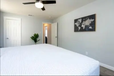 a bedroom with a large white bed with a ceiling fan at Charming 2BR Condo with Onsite Parking Included in Los Angeles