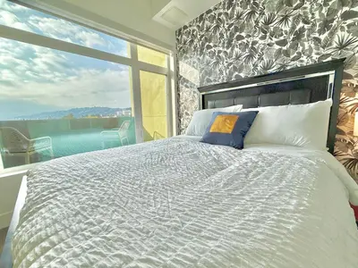 a bedroom with a large bed and a large window at Top Floor Hollywood 1BR Condo with Views in Los Angeles